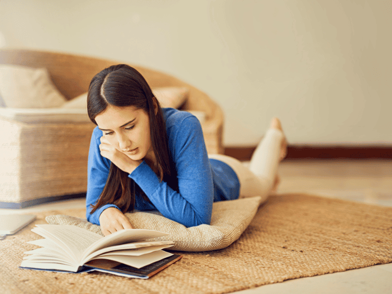 A woman laying on the floor reading a book.