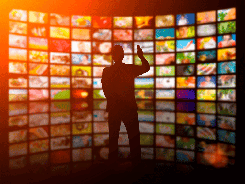 A man is standing in front of a television screen.