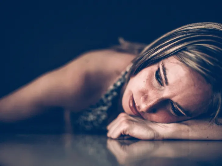 A woman is laying down on a table, conveying sadness through creative writing techniques.