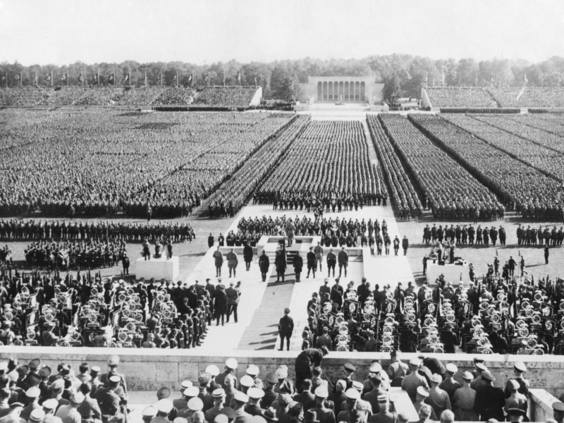 An old photo depicting a large crowd in front of a monumental building.
