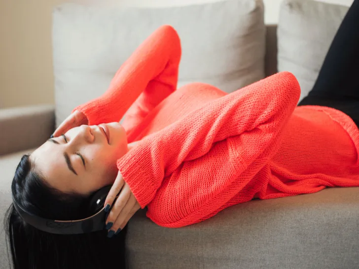 A woman examining the impact of music on her mood while relaxing on a couch.
