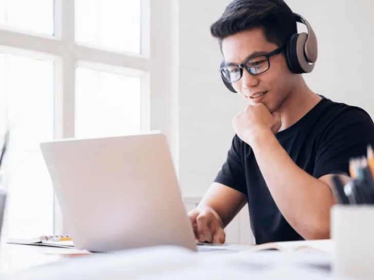A man using headphones is working on a laptop.