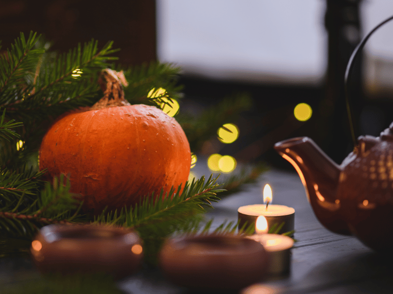 A teapot next to a pumpkin.