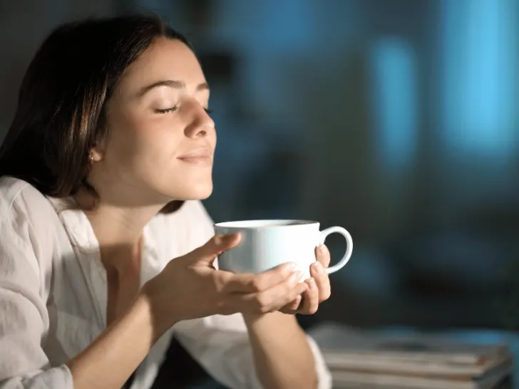 A woman is savoring the aroma of her coffee.