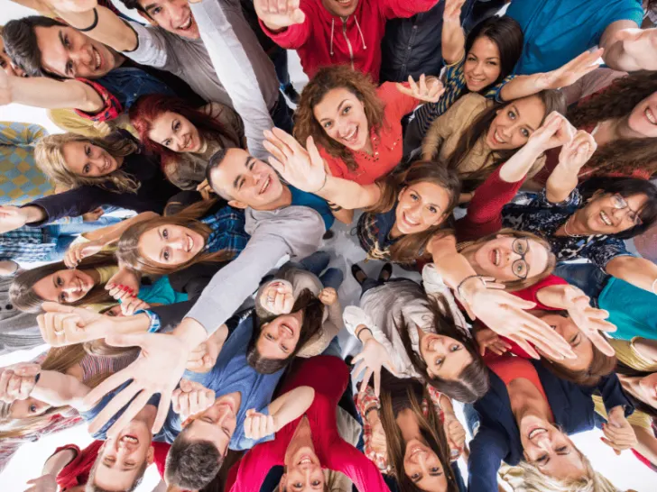 A circle of individuals greeting by waving.