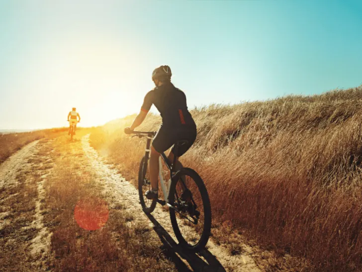 Two people riding bikes on a dirt road at sunset, engaging in their favorite outdoor activity.