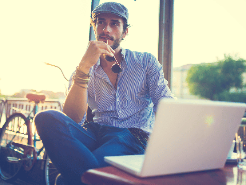 A man sitting at a table with a laptop, contemplating his favorite place in the world.