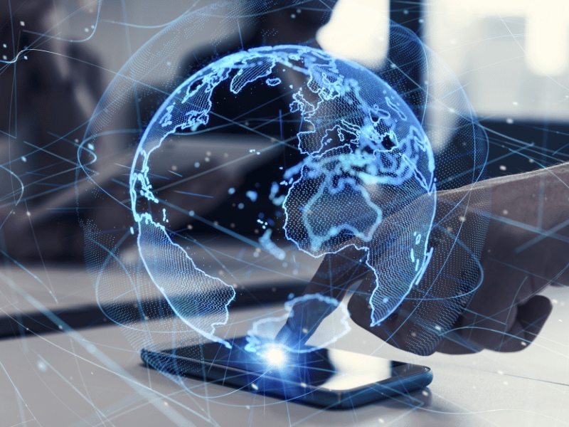 A person is touching a phone showcasing a globe, symbolizing the vastness and connectivity of the internet that has transformed our global communication landscape over the past 100 years.