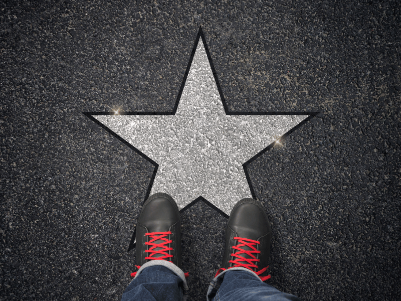 A person showcasing their talents next to a star on the street.