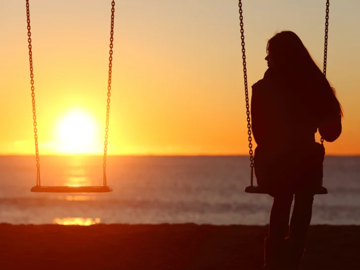 A woman gracefully enjoying solitude on a swing at sunset, embracing the art of being alone.